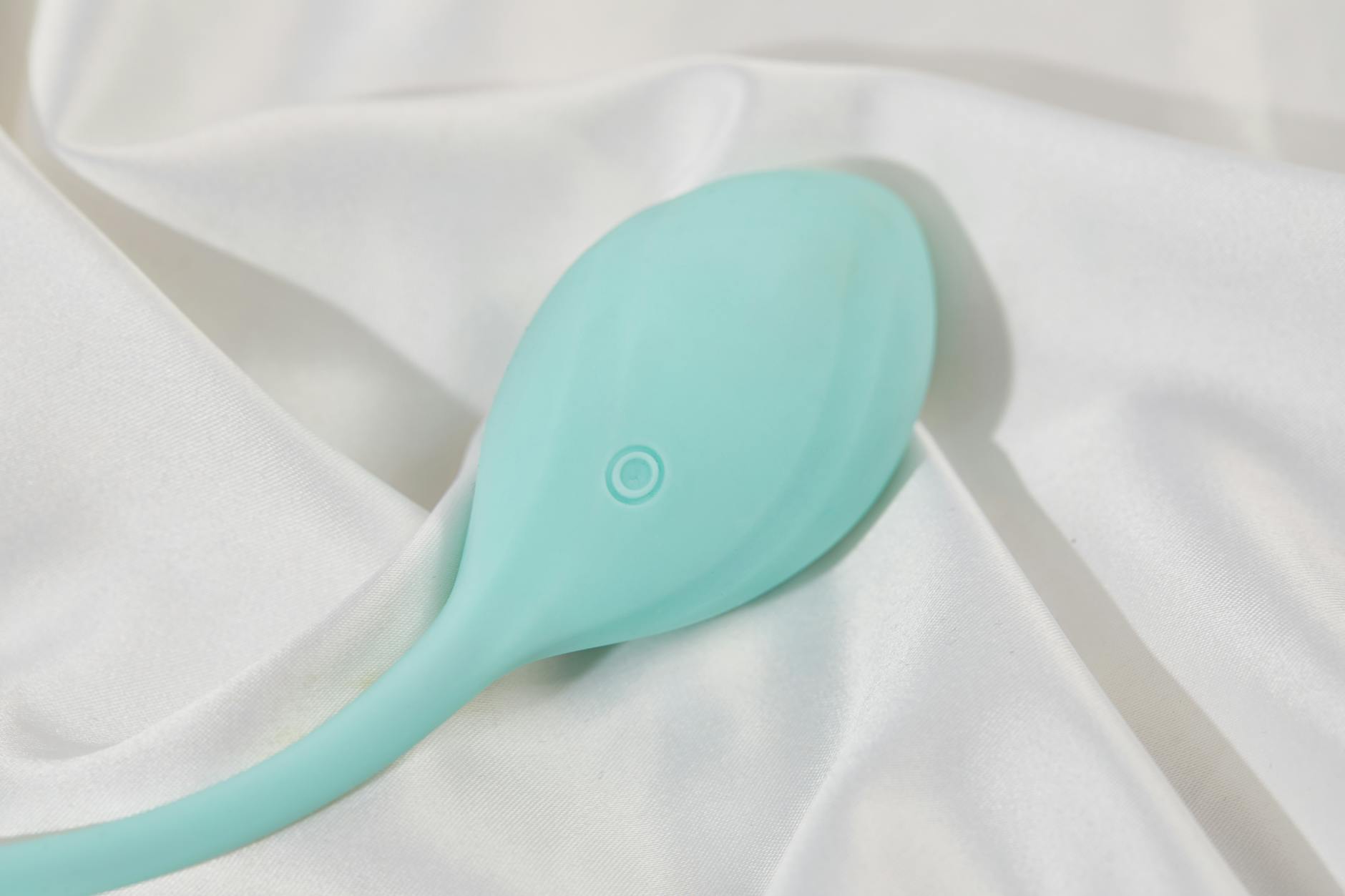 Teal lemon vibrator on soft white silk, representing pleasure without pressure