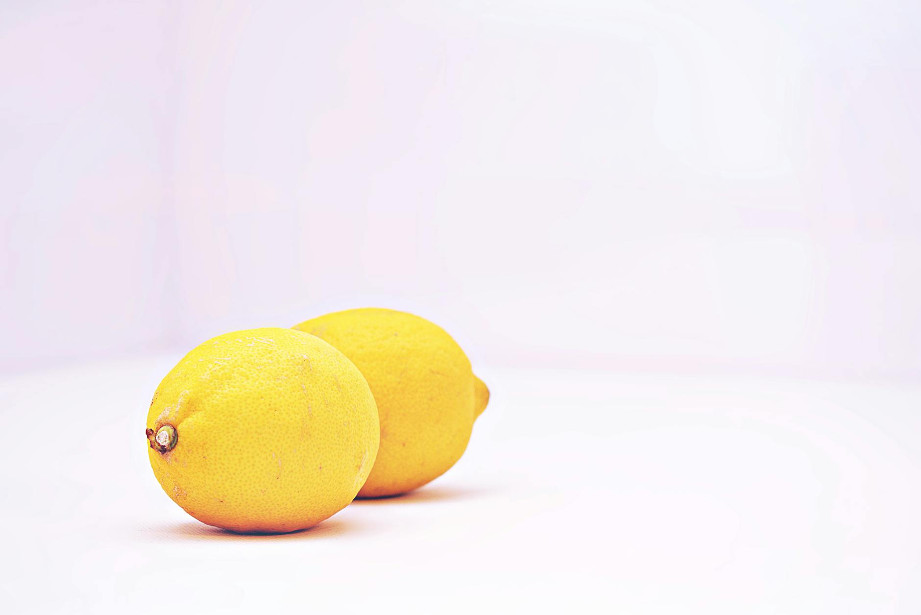 Close-up of a hand holding an orange vibrator against a minimalistic purple backdrop, showcasing modern sensuality.