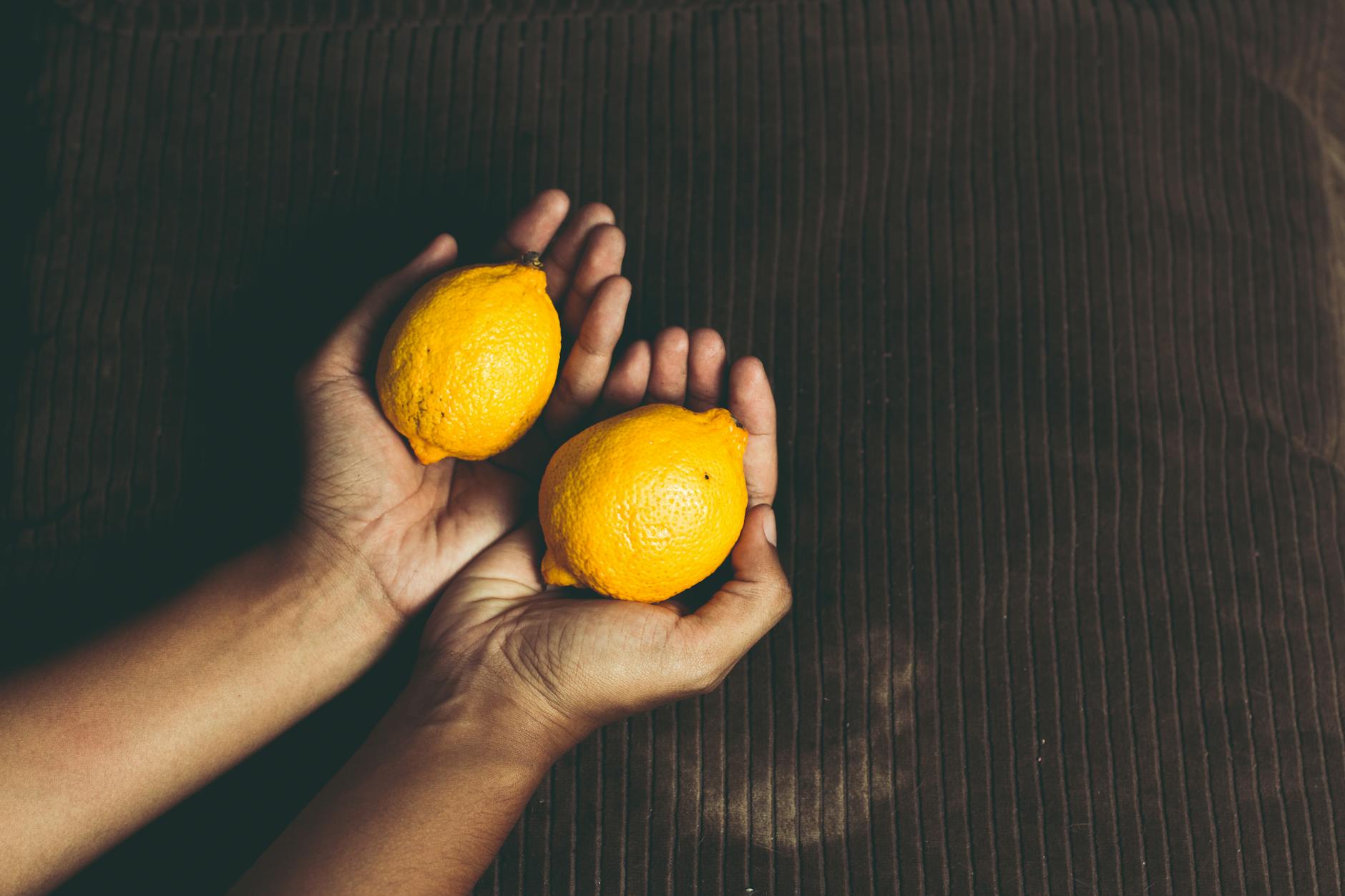 Two fresh lemons held in cupped hands, representing renewal and gentle care