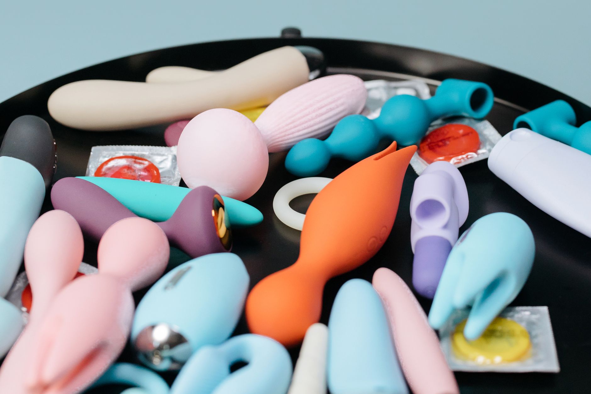 A vibrant collection of lemon vibrators and clitoral toys on a black tray, featuring diverse shapes and colors