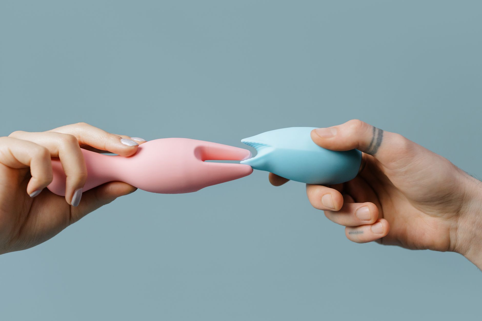 Hands holding pastel-colored silicone toys during pregnancy wellness journey