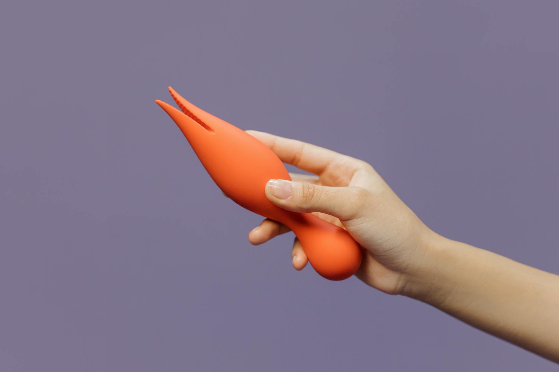 Hand holding a lemon-colored vibrator against a minimalist backdrop