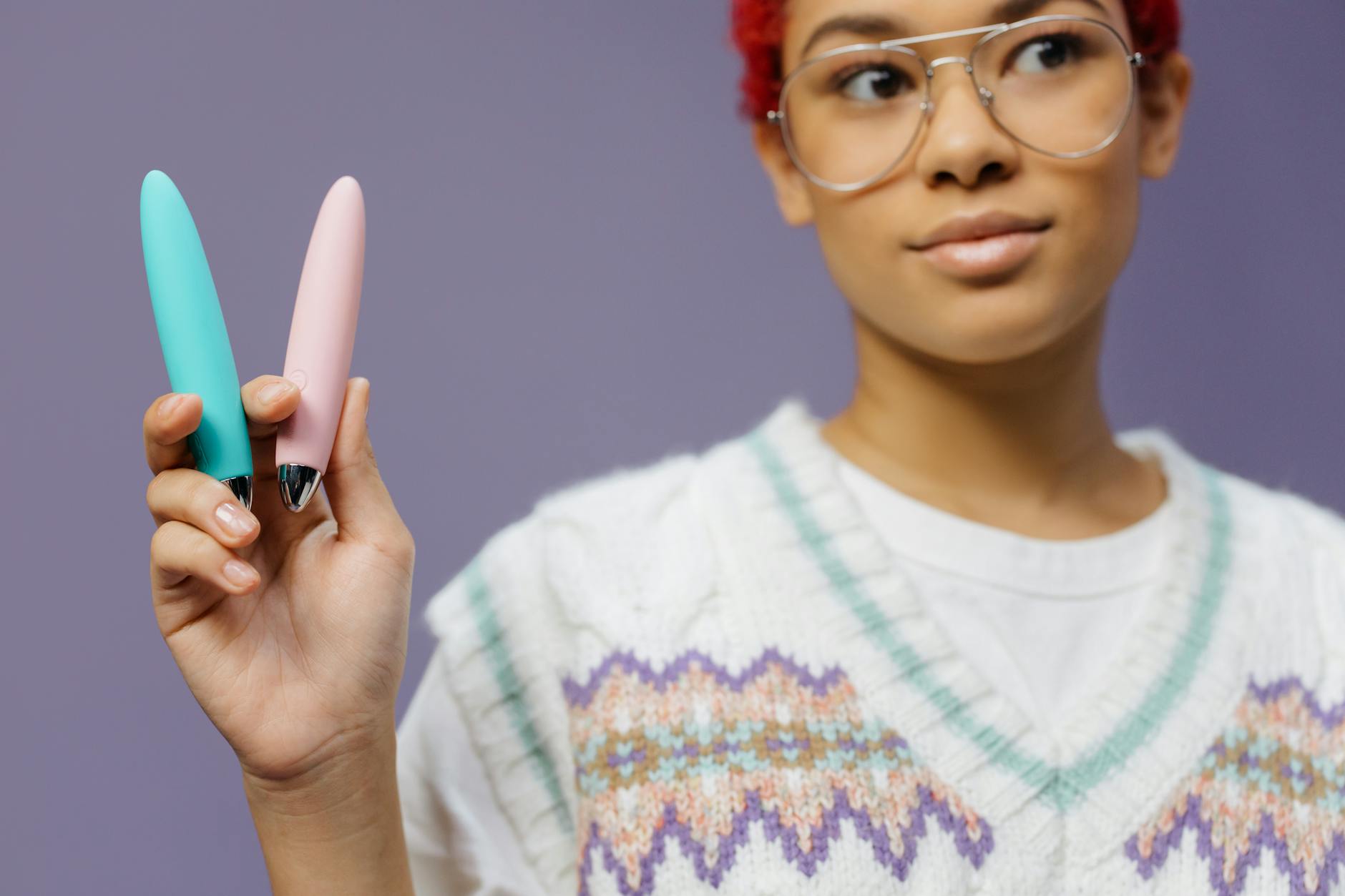 Hands holding a sleek blue lemon clitoral vibrator against a purple background