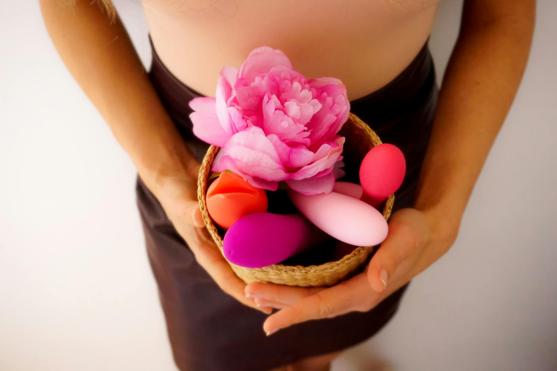 A basket containing colorful vibrators and flowers on a soft background